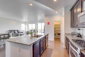 A modern kitchen with granite countertops, dark cabinetry, and stainless steel appliances. - Near Rocky Mountain Arsenal: Commerce City Home (Commerce City)