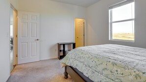 Een slaapkamer met een bed, een raam, een deur en een klein tafeltje.