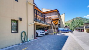 A modern building with a parking area, a covered walkway, and a mountain in the background. - Vail Top-floor Condo w/ Deck & Mountain Views! (Vail)