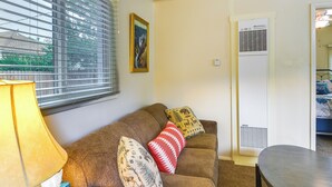 Una sala de estar con un sofá marrón, una mesa y una ventana con persianas.