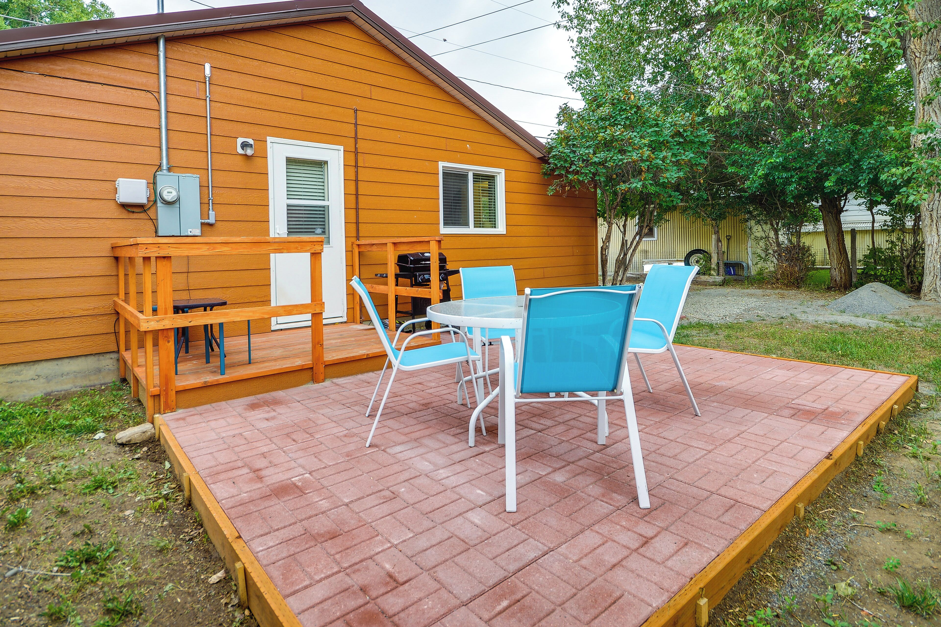 A wooden deck with a table and chairs, a grill, and a wooden railing.