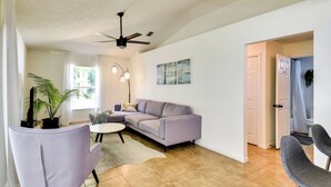Un salon avec un canapé d’angle, une table basse ronde et un ventilateur de plafond.