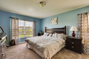 A bedroom with a bed, nightstands, a dresser, a window with curtains, and a ceiling light.