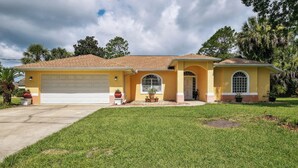 A two-story house with a garage, a front porch, and a well-maintained lawn. - Palm Coast Escape: Screened Lanai, Saltwater Pool! (Palm Coast)