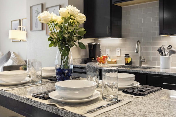 A kitchen with a granite countertop, white plates, bowls, and a vase with white flowers. - 5 Mi to Red Rocks! Updated Home Near Hiking Trails (Golden)