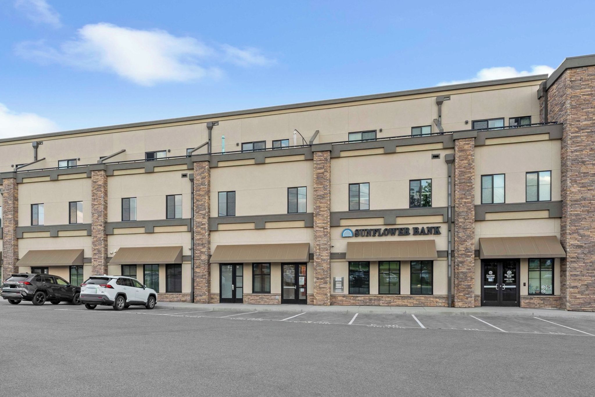 A multi-story building with a 'Sunflower Bank' sign, parking spaces, and a clear sky.