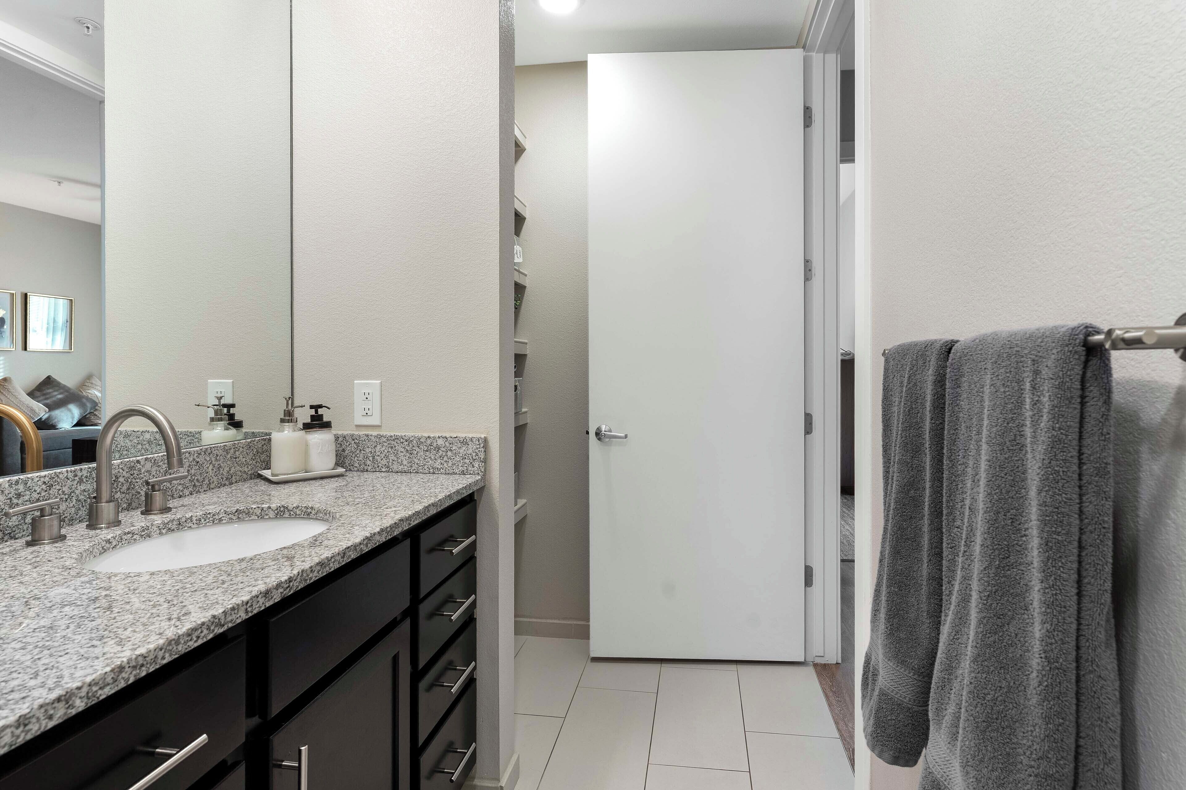 Een badkamer met twee wastafels, een handdoekrek en een deur naar de douche.