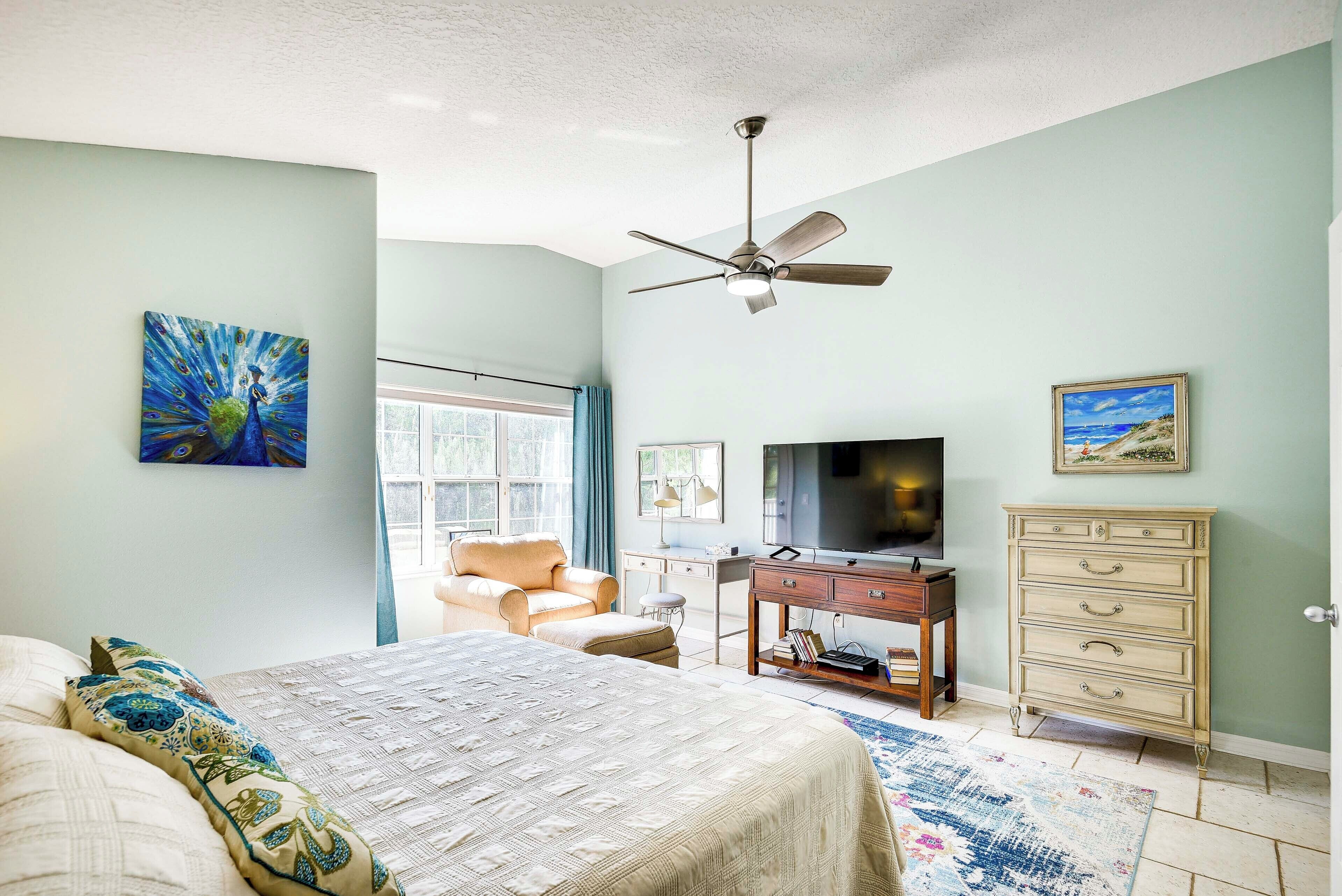 A bedroom with a bed, a desk, a television, and a dresser.