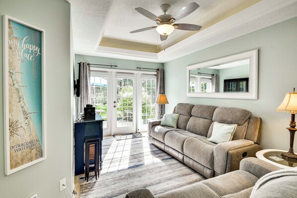 A living room with a ceiling fan, a sofa, a coffee table, and a rug.
