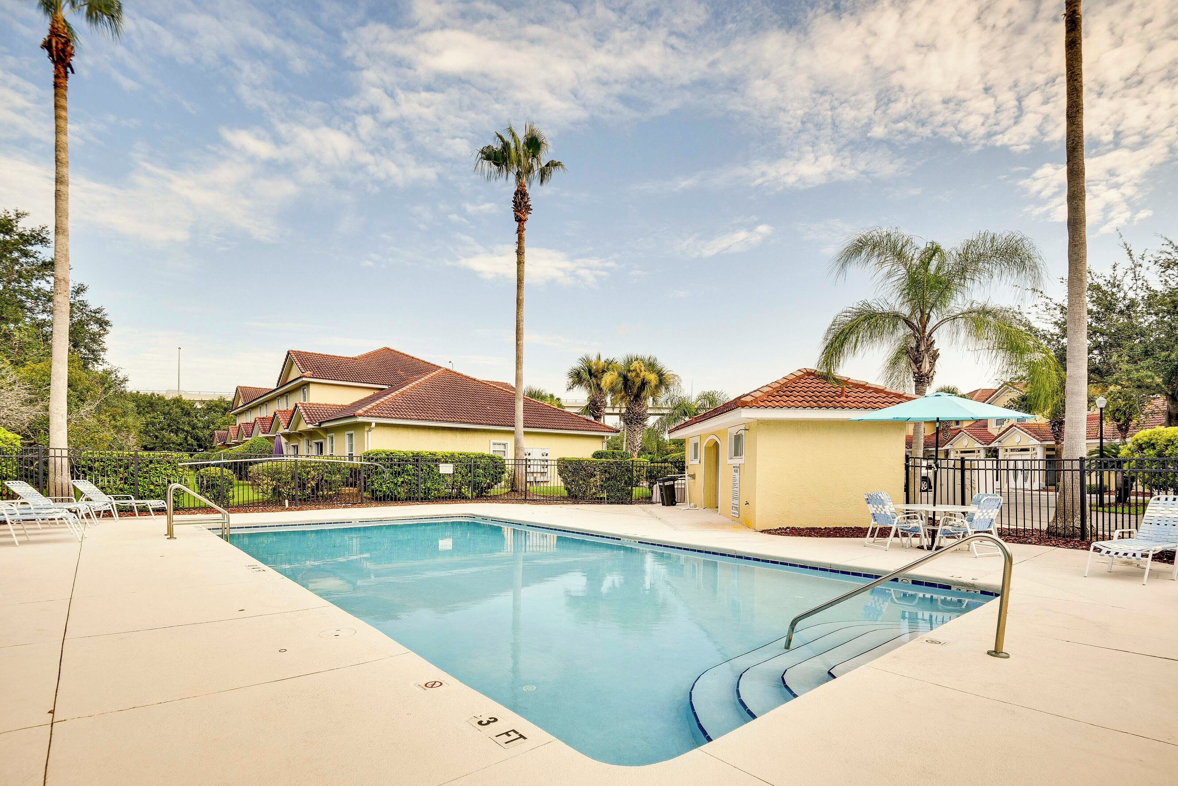 A swimming pool with a 3 FT depth marker, surrounded by lounge chairs and palm trees.