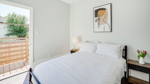 Une chambre à coucher comprenant un lit, une table de chevet, une lampe, un tableau encadré et un vase avec des fleurs.
