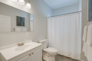A bathroom with a white sink, toilet, and shower curtain.