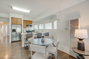 A modern kitchen with a refrigerator, microwave, and dining area with chairs and a table.