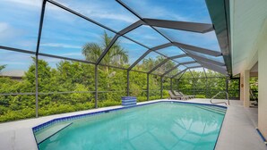 Piscina com cobertura de vidro, rodeada por vegetação exuberante e céu claro.