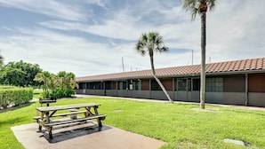 A building with a tiled roof, a grassy area with a picnic table, and palm trees. - Close to Parks & Beaches! Naples Studio w/ Pool (Naples)