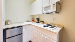 A compact kitchen with white cabinets, a built-in microwave, a stove, and a dishwasher. - Close to Parks & Beaches! Naples Studio w/ Pool (Naples)