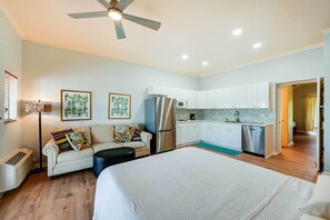 A modern hotel room with a large bed, a kitchenette, a ceiling fan, and a view of the adjacent room. - Bright Naples Vacation Rental: Close to Waterfront (Naples)