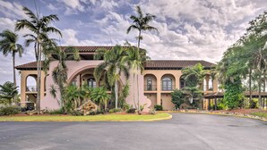 A large building with a curved driveway, palm trees, and a clear sky. - Naples Vacation Rental w/ Grill, Resort Pool! (Naples)