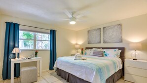 Quarto bem arrumado com uma cama, mesas de cabeceira, escrivaninha e ventoinha no teto.