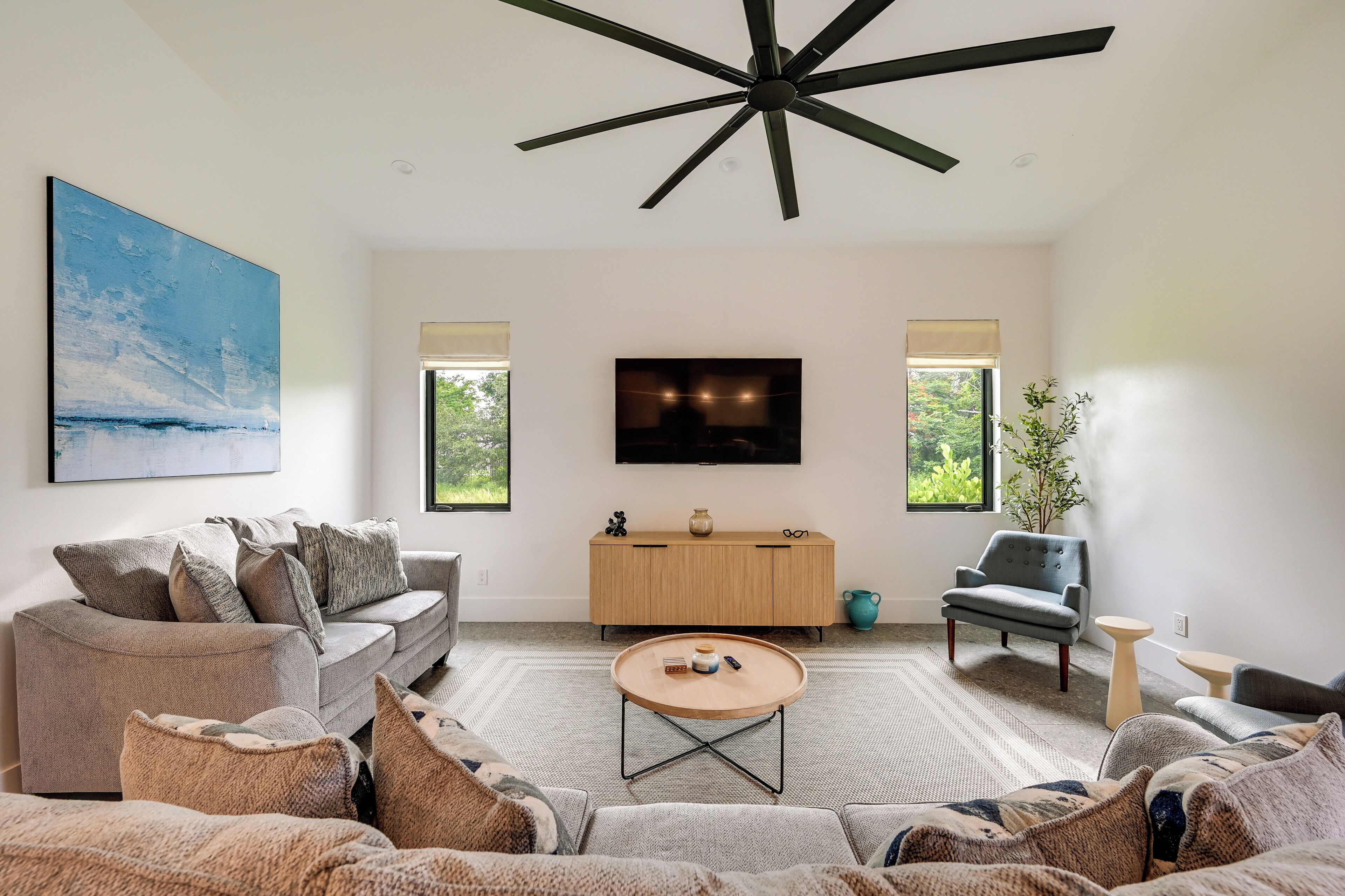 Un salon moderne avec un canapé, une table basse, un téléviseur et un ventilateur de plafond.