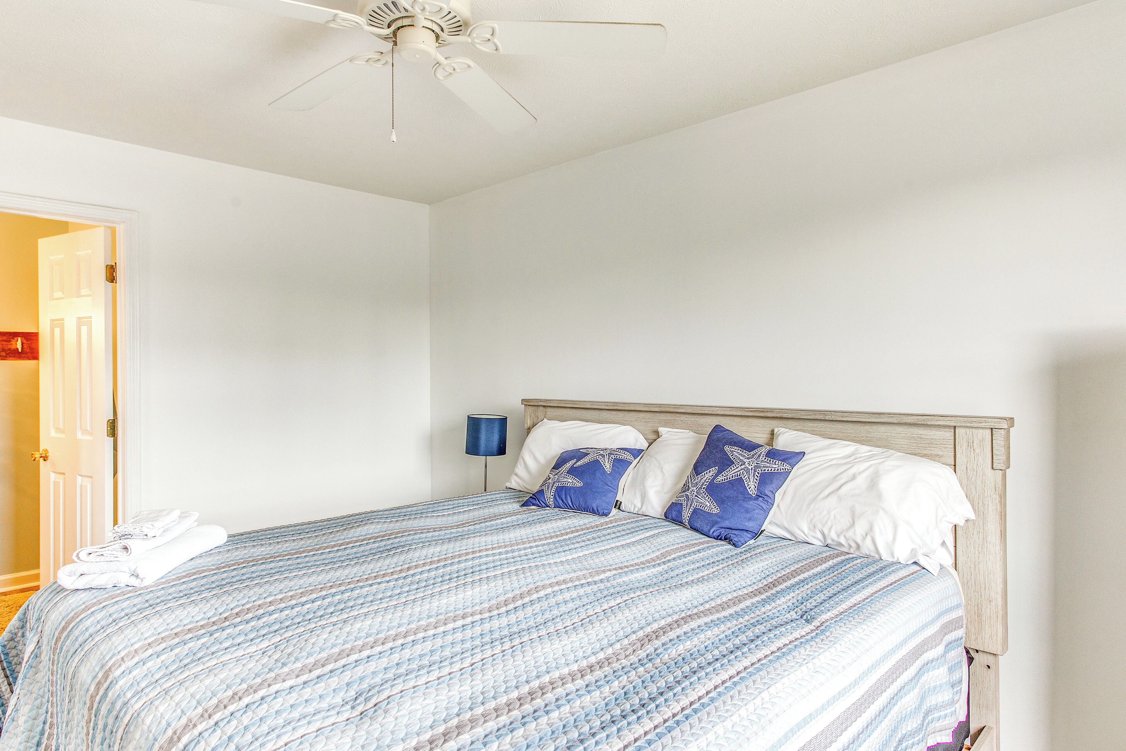 A neatly made bed with a striped bedspread, a wooden headboard, and two pillows with star patterns.