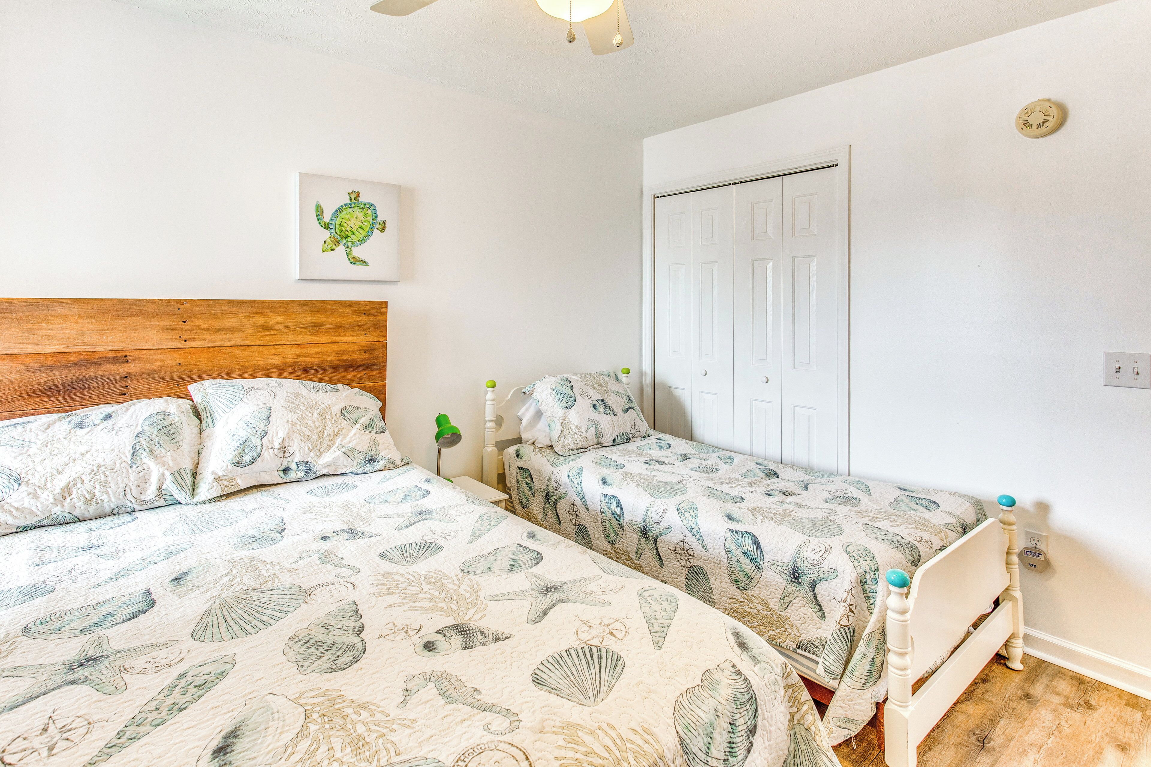 A bedroom with two beds, each with a wooden headboard and a white wall with a framed picture.