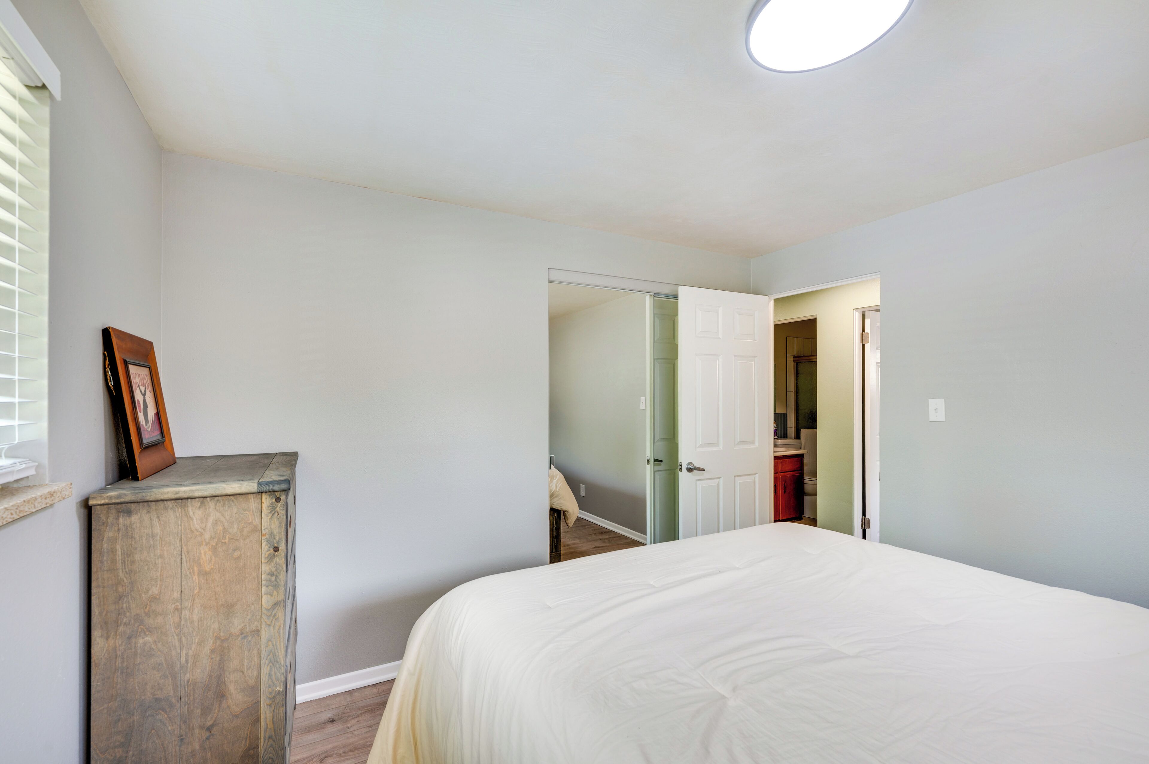 Un dormitorio con una cama, un armario de madera y una puerta que da a otra habitación.