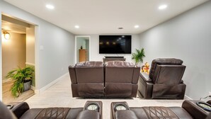 Un cine en casa con dos sillones de cuero reclinables, un televisor de pantalla plana y una planta pequeña.