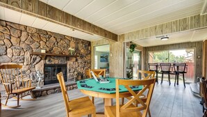 Una habitación acogedora con chimenea de piedra, sillas de madera y una mesa de póker verde.