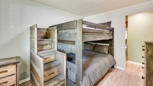 Una cama individual con estructura de madera y cajones, una mesita de noche y una pared de color claro.