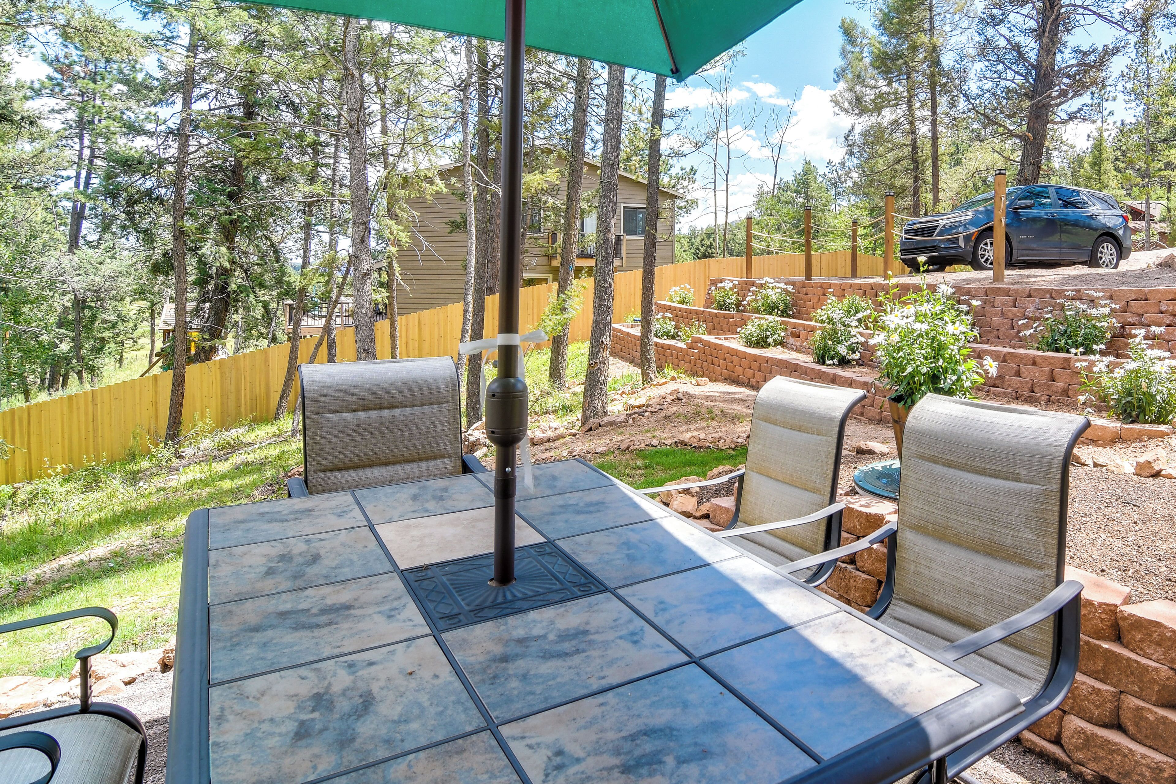 A patio with a table and chairs, surrounded by a wooden fence and a brick wall.