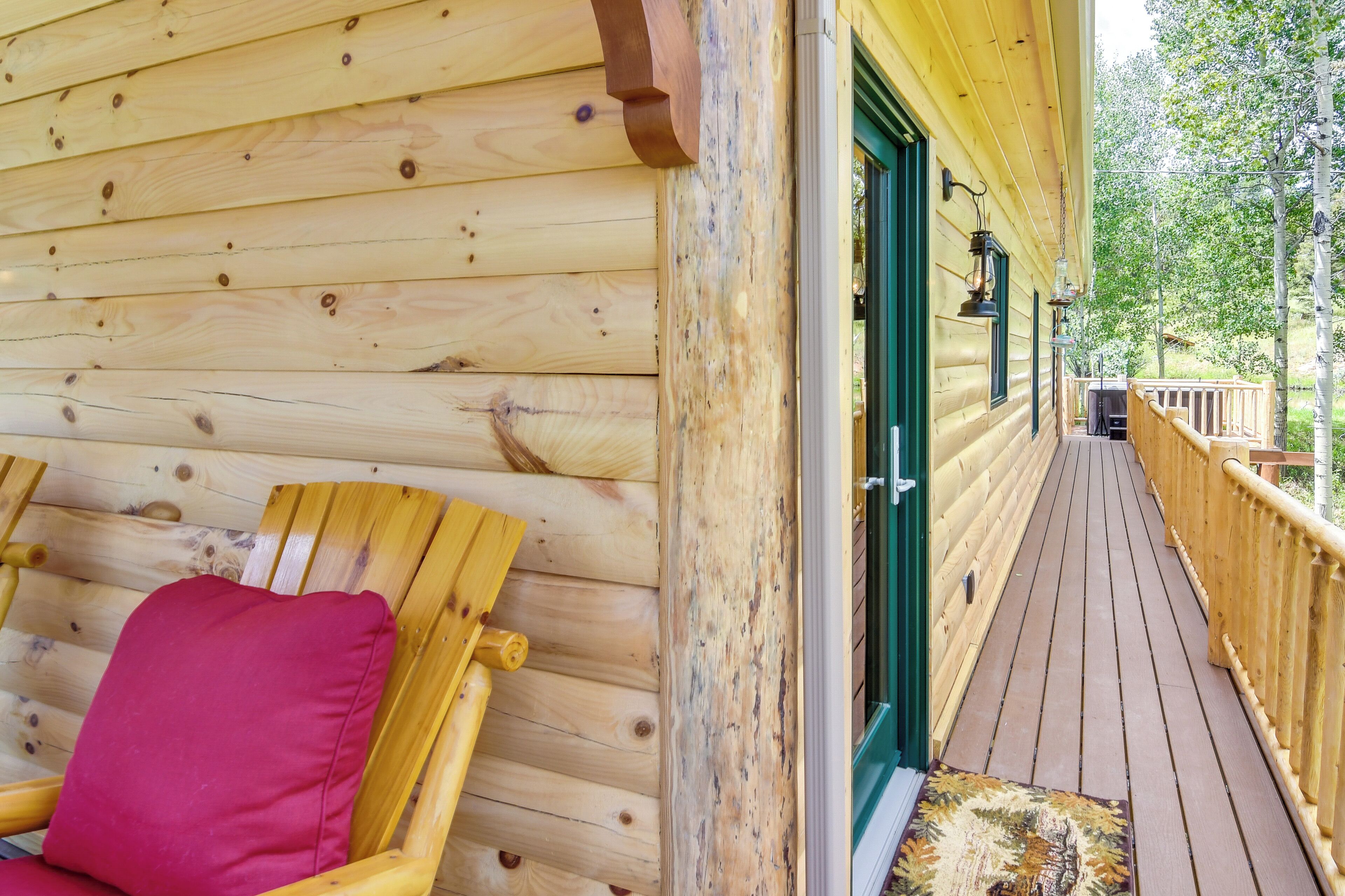 A wooden deck with a wooden chair and a door leading to a covered area.