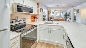 Une cuisine moderne avec des meubles blancs, des appareils en acier inoxydable et un plan de travail en bois.