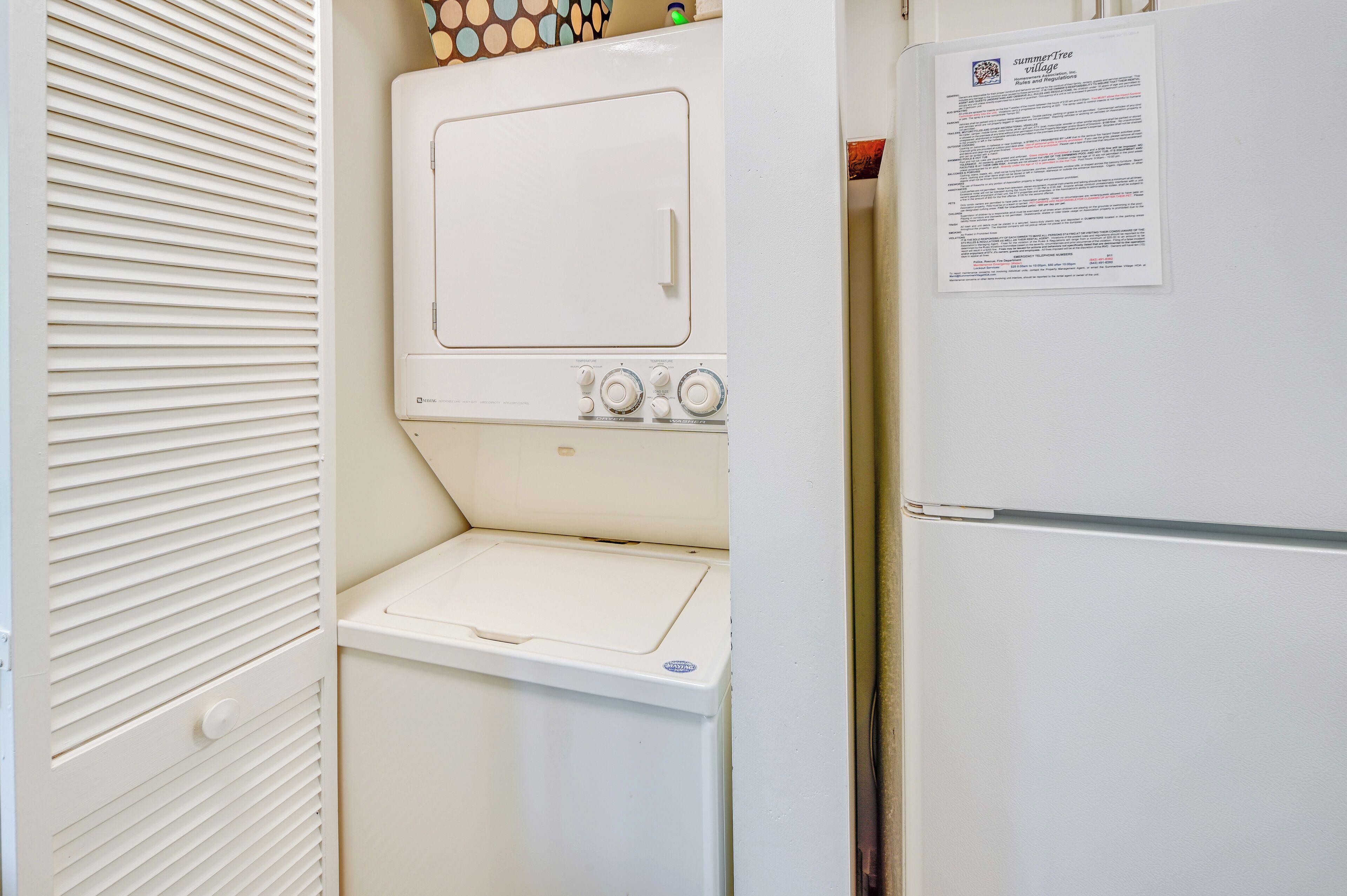 A laundry area with a washer and dryer, a refrigerator, and a door with a bulletin board.