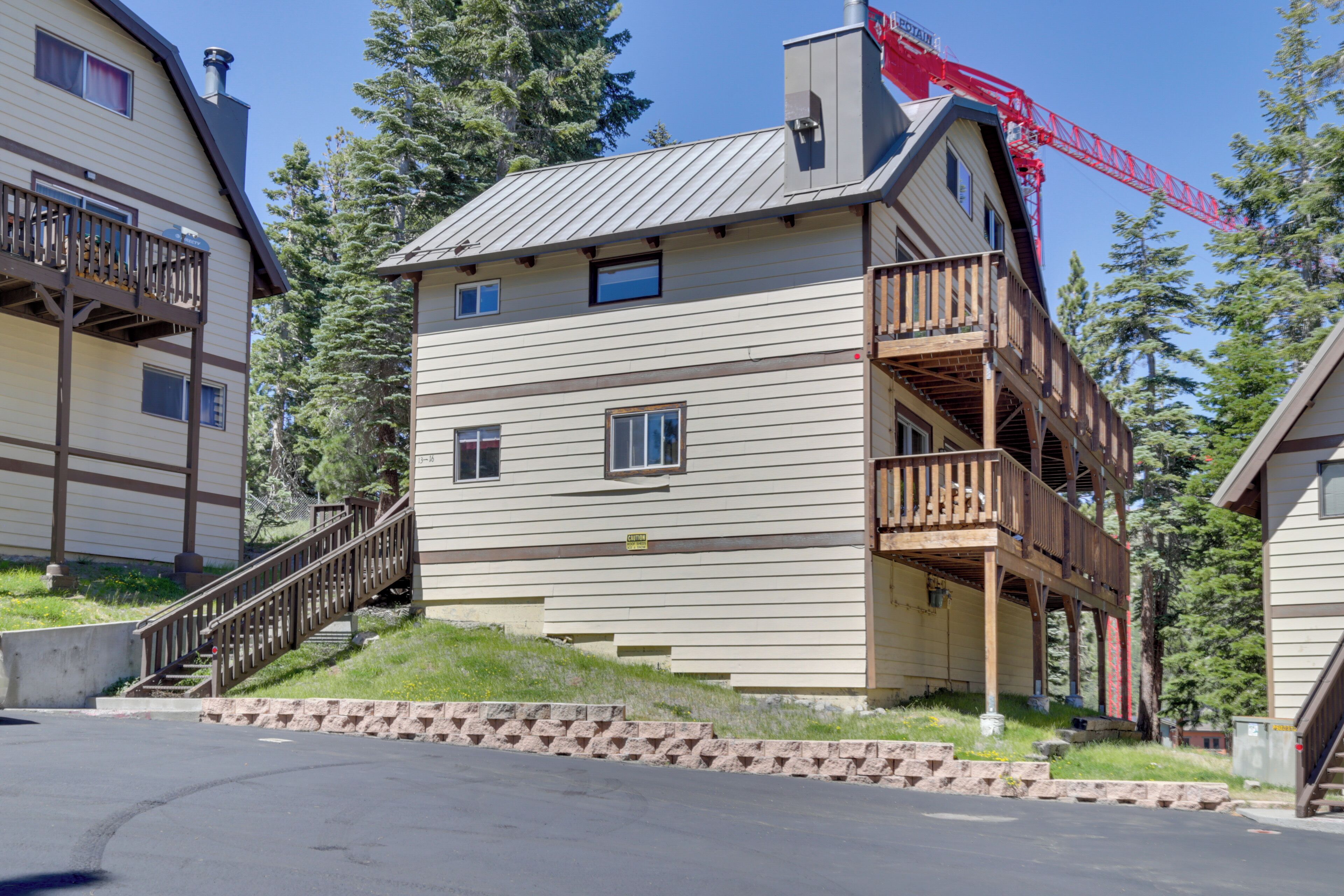 A multi-story building with a balcony on the second floor, a chimney, and a red crane in the background.