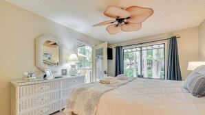 A bedroom with a large bed, a dresser, a ceiling fan, a window with curtains, and a view of trees. - Private Deck & Pool Access: Myrtle Beach Getaway! (Myrtle Beach)