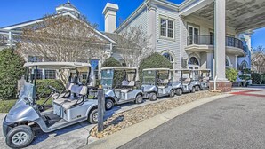 A row of golf carts parked in front of a large, white building with a balcony. - ~ 6 Mi to Ocean w/ Pool & Golf: Myrtle Beach Condo (Myrtle Beach)