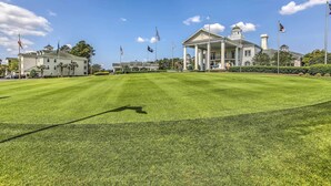 A large, well-maintained lawn with a grand building featuring a central pavilion and multiple flags. - ~ 6 Mi to Ocean w/ Pool & Golf: Myrtle Beach Condo (Myrtle Beach)