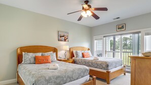 A bedroom with two wooden beds, a ceiling fan, a large window with a view of trees, and a wooden dresser. - ~ 6 Mi to Ocean w/ Pool & Golf: Myrtle Beach Condo (Myrtle Beach)