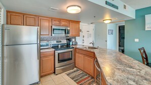 A kitchen with wooden cabinets, stainless steel appliances, a granite countertop, and a tiled floor. - Pool Access: Oceanfront Myrtle Beach Getaway! (Myrtle Beach)