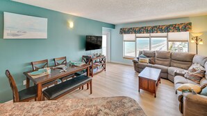 A living room with a dining area, a sofa, a TV, and a view of the ocean. - Pool Access: Oceanfront Myrtle Beach Getaway! (Myrtle Beach)