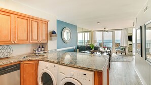Une cuisine dotée de plans de travail en granit, d’armoires en bois et d’un lave-linge et d’un sèche-linge encastrés.