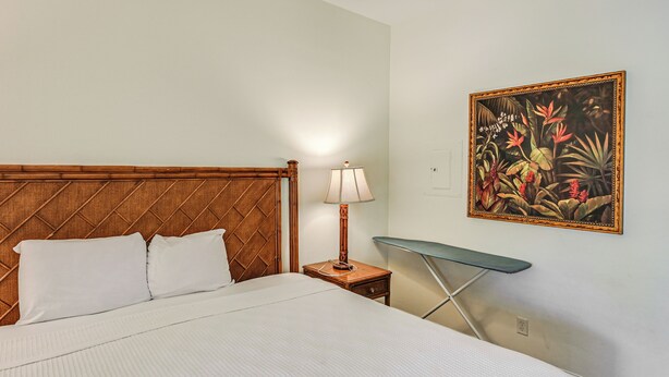 A neatly made bed with a wooden headboard, a bedside lamp, and a small table with a green surface. - Naples Resort Retreat w/ Heated Pool Access! (Naples)