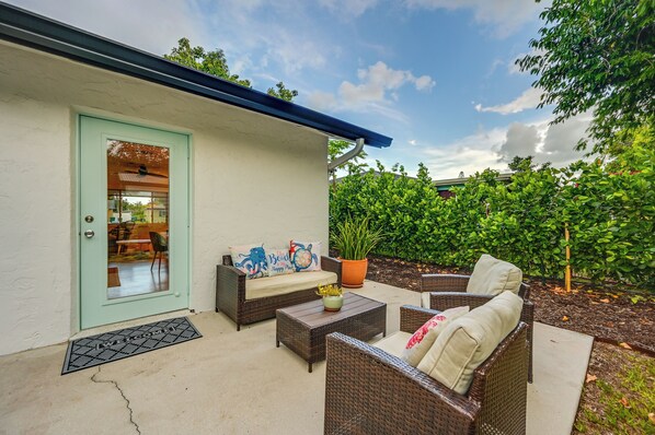 A patio area with wicker furniture, a potted plant, and a door with a window. - Sunny Florida Escape w/ Patio, Grill & Fire Pit! (Naples)