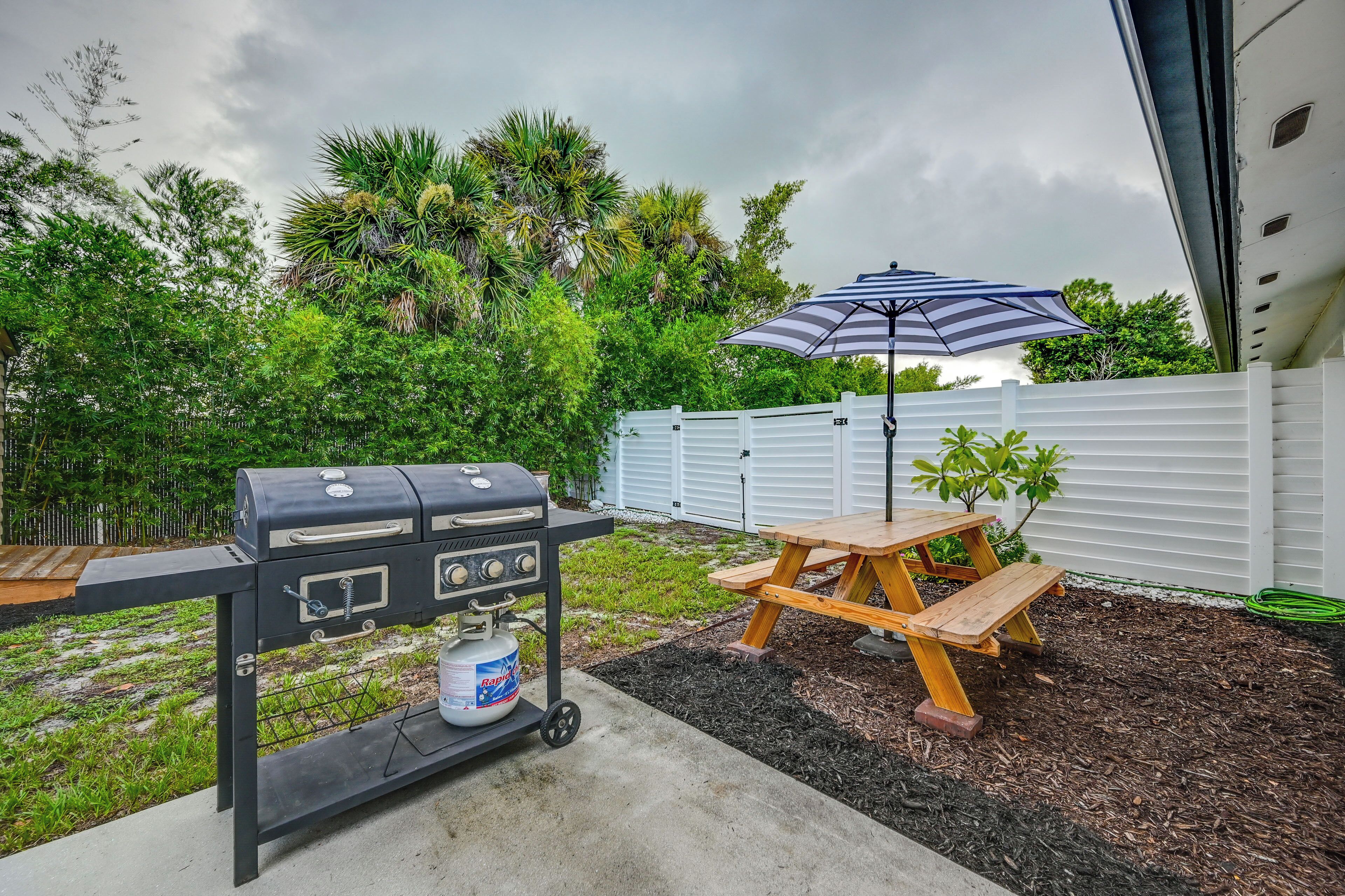 A backyard with a barbecue grill, a picnic table, and an umbrella.