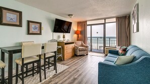 A living area with a sofa, chairs, a TV, a table, and a view of the ocean. - Ocean-view Myrtle Beach Condo w/ Beach Access! (Myrtle Beach)