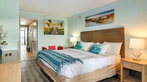 A neatly arranged hotel room with a large bed, bedside tables, a desk, and a chair. - Ocean-view Myrtle Beach Condo w/ Beach Access! (Myrtle Beach)