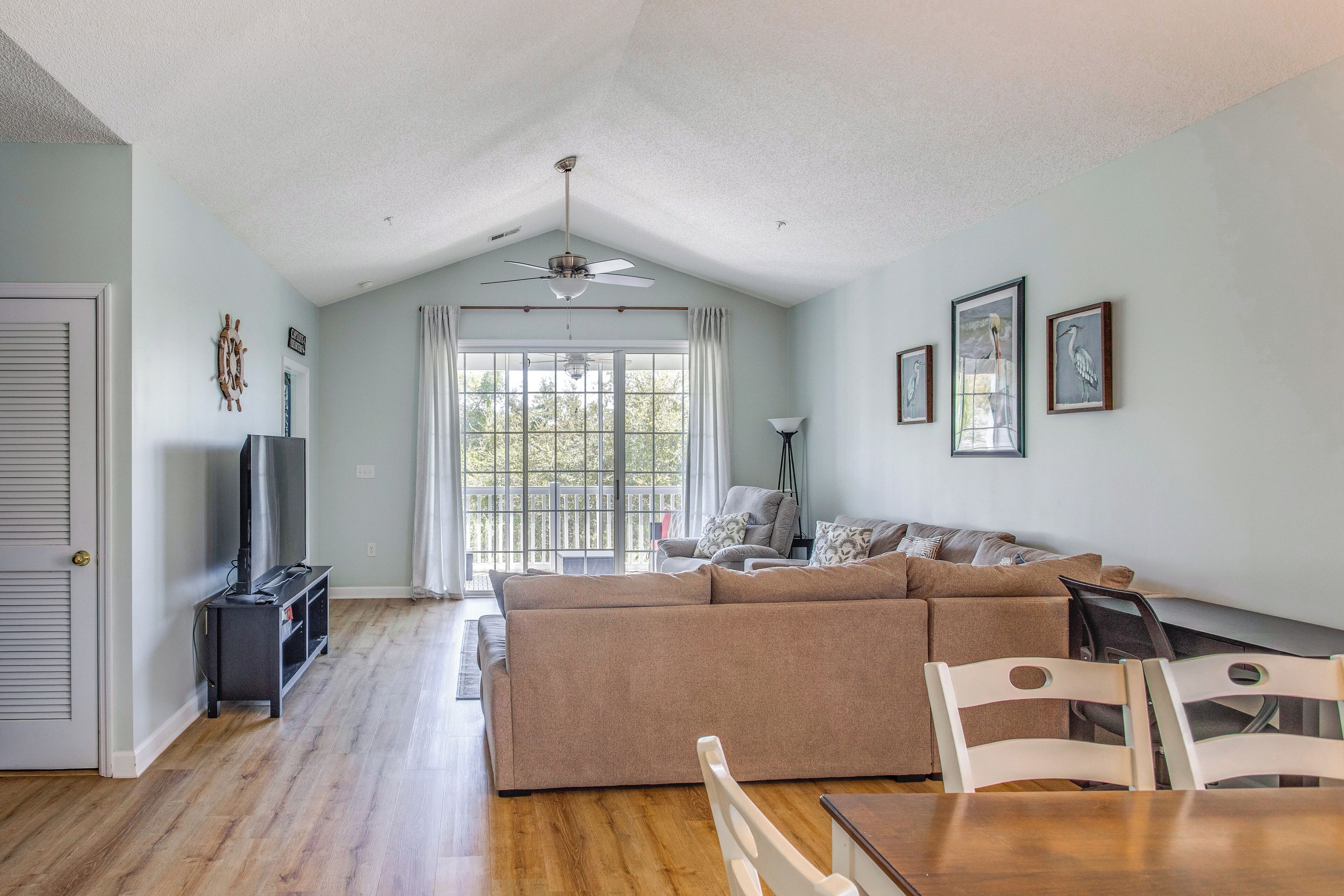 A living room with a sofa, chairs, a TV, and a ceiling fan.