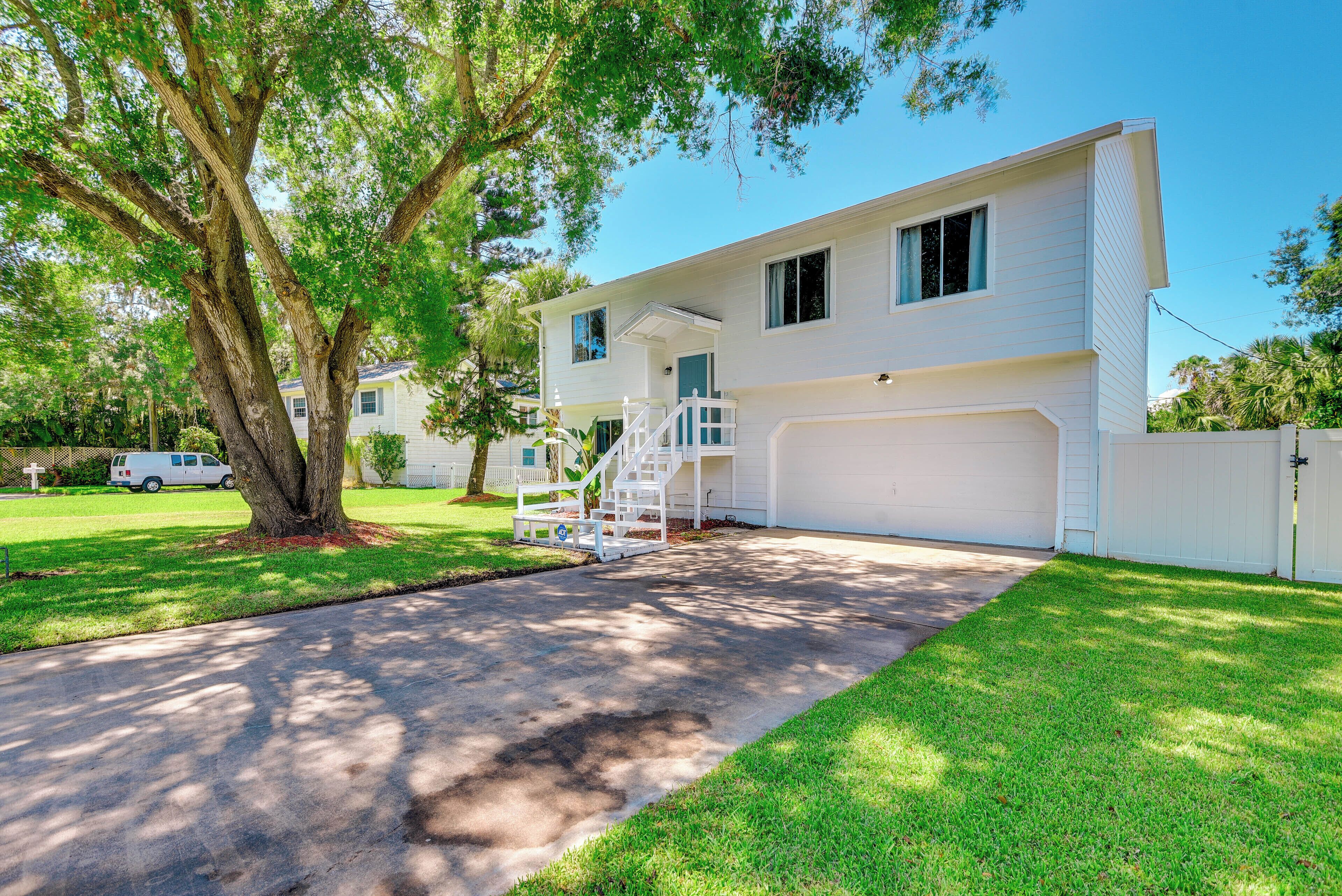 A two-story house with a front garage, a staircase leading to the second floor, and a large tree in the front yard.