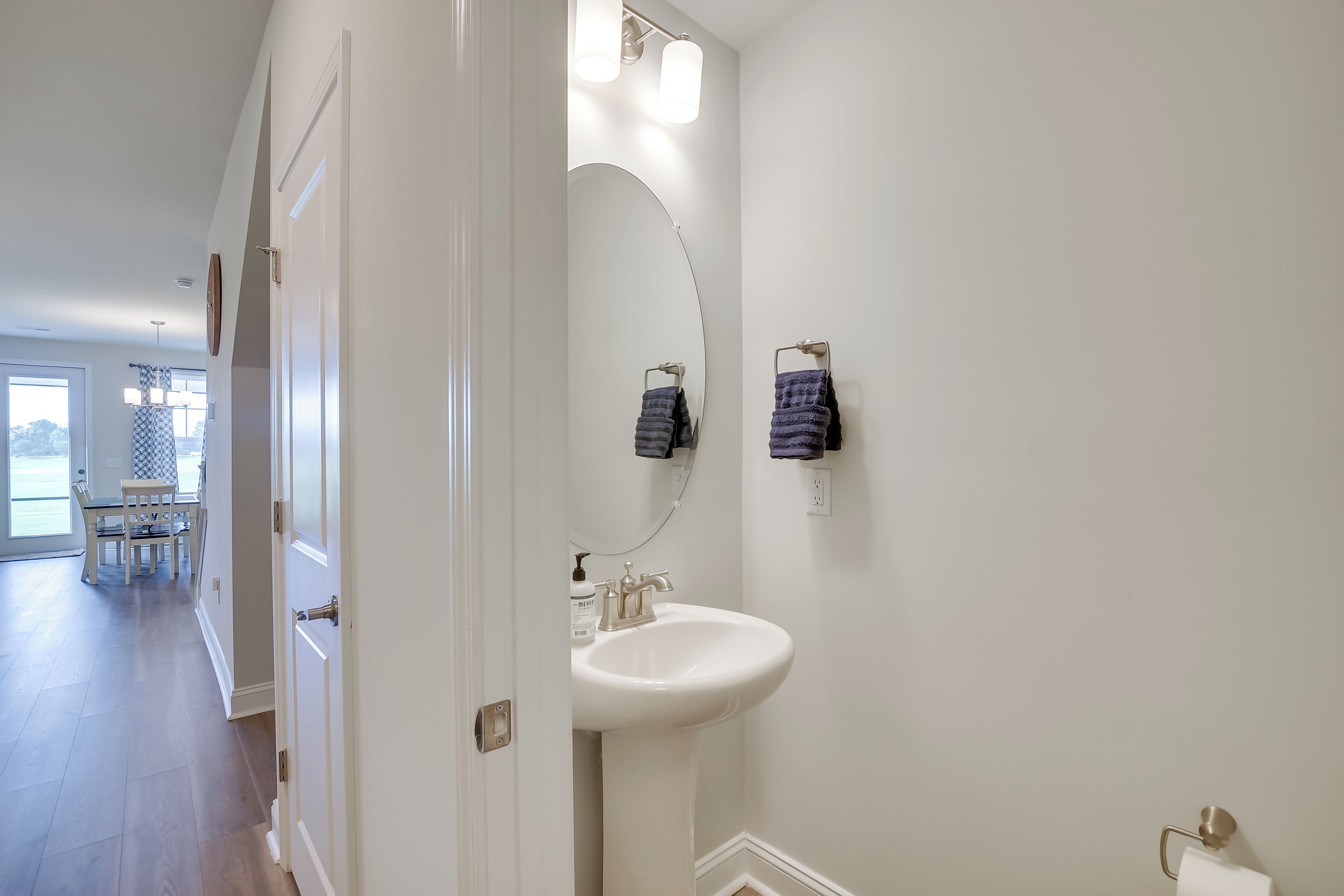 A bathroom with a white sink, a mirror, and two towels hanging on the wall.